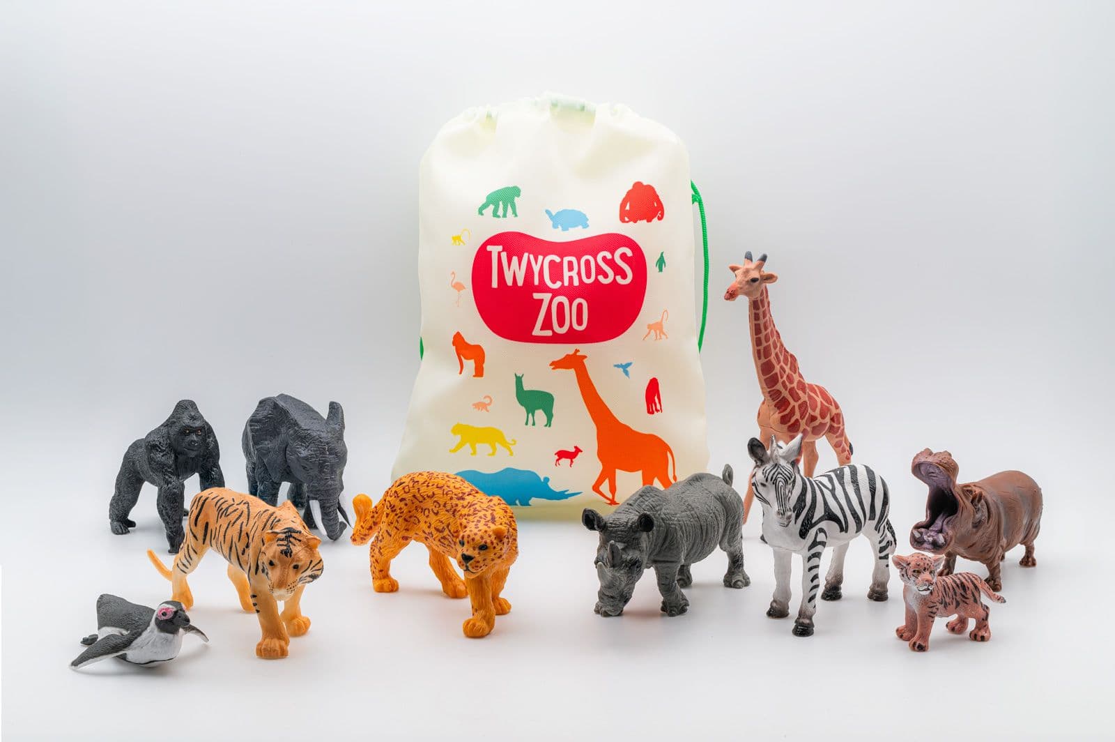 Zoo drawstring bag surrounded by toy animal figures, including a giraffe, zebra, gorilla, elephant, tiger, leopard, rhinoceros, hippopotamus, penguin and tiger cub.